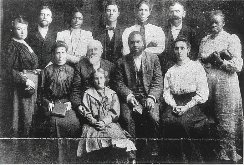 Grupa kobiet i mężczyzn, białych i czarnych, pozuje do wspólnego zdjęcia; w środku siedzi William Seymour