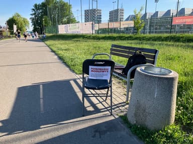 Krzesło z kartką „Potrzebujesz modlitwy?” przy ścieżce nad rzeką w Rzeszowie